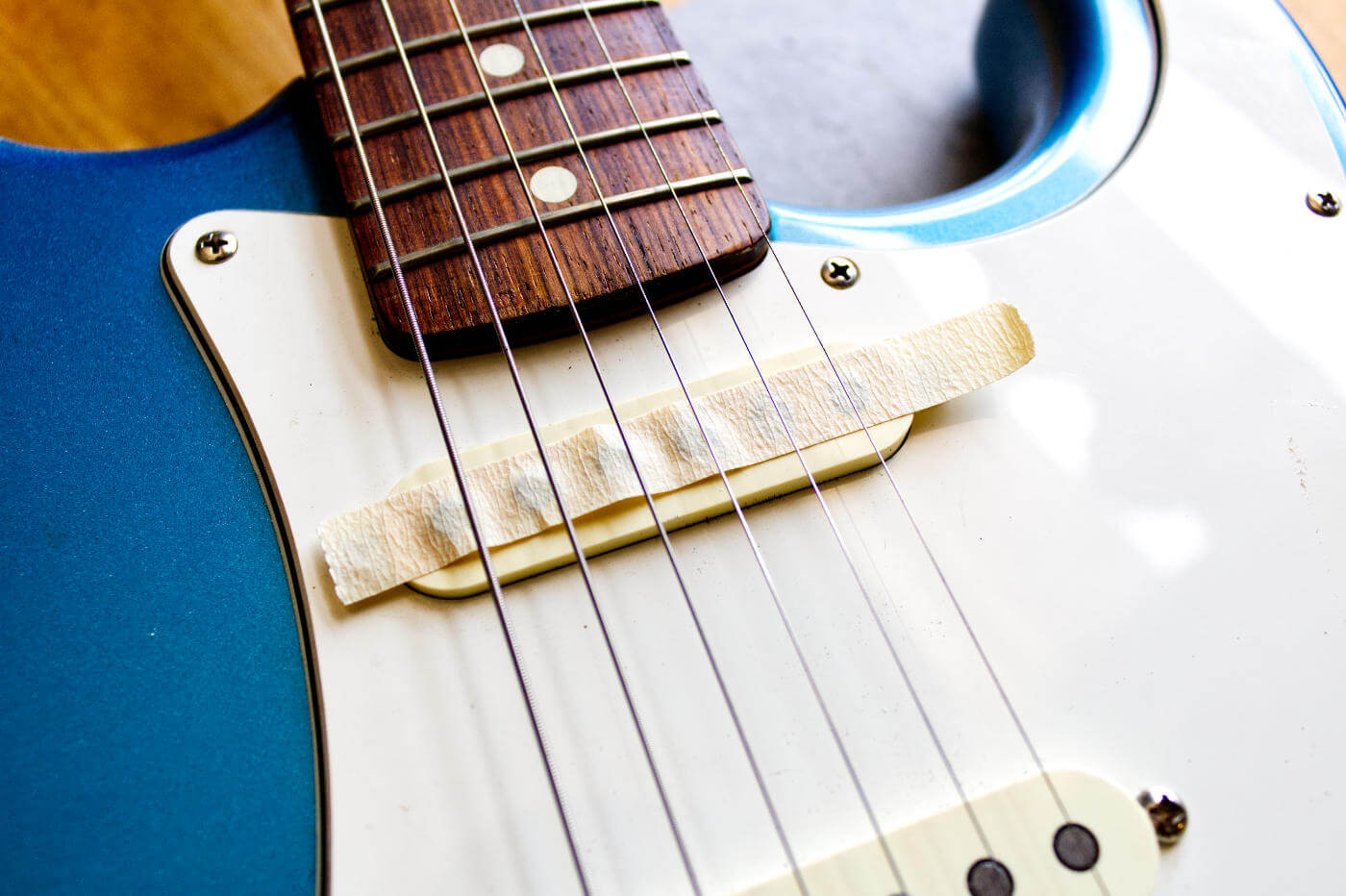 Fender strat with tape on Neck pickup to remove metal filings